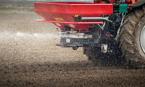 Fertilizer being spread by the back of a tractor