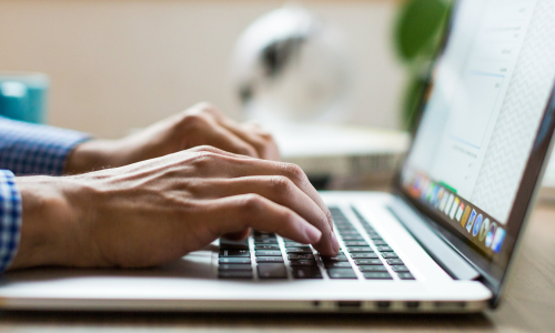 A close up of hands typing on a laptop